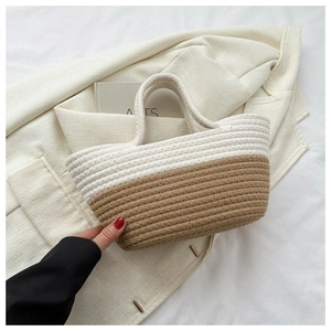 Détail du sac seau bicolore tressé posé sur une veste blanche dans un cadre de vie quotidien