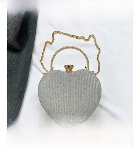 Close-up of heart-shaped evening bag with silver sequins and gold metal handle