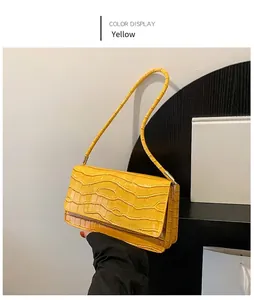 Détail du sac baguette jaune montrant la texture crocodile et le design en accordéon