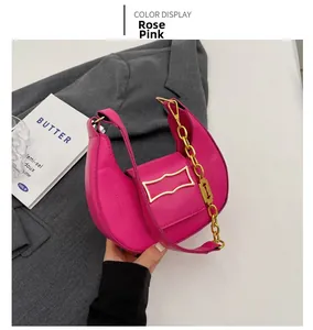 Détail du sac croissant rose avec chaîne dorée et lanière en cuir sur costume gris