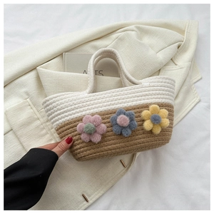 Détail d'un sac cabas tissé bicolore orné de fleurs de soleil colorées en peluche