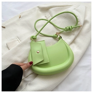 Detail of lime green half-moon crossbody bag with knot strap on white tweed blazer