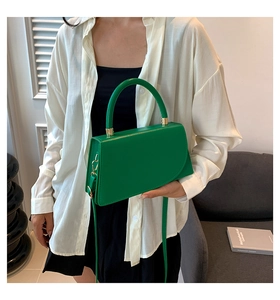 Close-up of vibrant green top-handle bag with gold hardware and leather strap