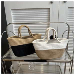 Gros plan de sacs cabas en corde de coton bicolores kaki et blanc sur une étagère