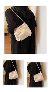Detail of cream white pleated cloud bag featuring sweet bow accents and chain strap