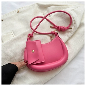 Detailed close-up of rose pink crescent bag with leather texture and knotted shoulder strap