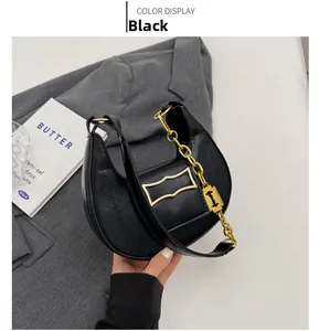 Détail d'un sac demi-lune noir avec bandoulière chaîne dorée et coutures verticales chic