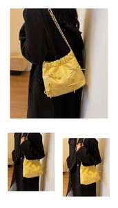 Close-up of yellow pleated bucket bag featuring delicate bows and metal chain strap