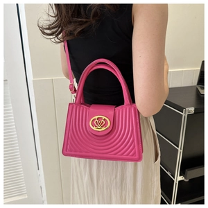 Detail of rose red leather handbag with gold metal clasp and adjustable shoulder strap