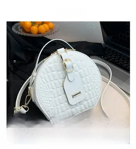Close-up of white crocodile pattern round bag with quilting and gold zipper details