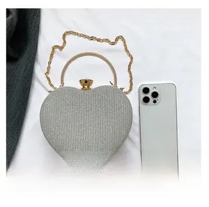 Detail shot of heart-shaped silver sequin clutch bag with gold handle and chain strap