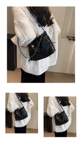 Detail of black pleated bucket bag with leather bows and silver chain strap