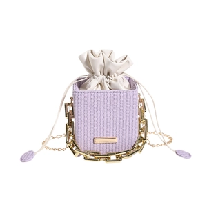 Chic lavender woven bucket bag featuring thick gold chain decor and a drawstring closure