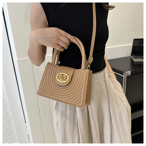 Detail van kaki PU-leren tas met gestikte boogpatronen en een gouden ronde sluiting