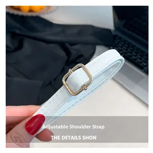 Close-up of adjustable white crocodile pattern strap with gold metal buckle and stitching