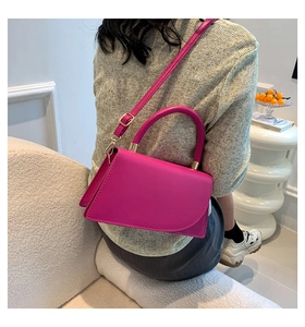 Detail of rose pink PU leather handbag with gold metal hardware and cylindrical handle