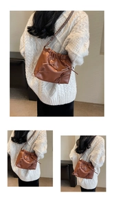 Close-up of brown pleated bucket bag featuring delicate ribbon bows and woven chain strap