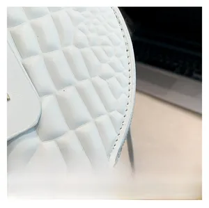 Close-up of premium white crocodile embossed texture on a stylish round handbag