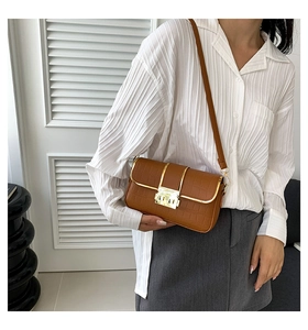 Detail of brown faux leather crossbody bag with crocodile pattern and gold clasp
