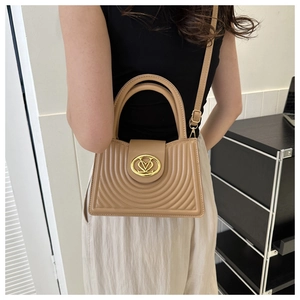 Detail van elegante beige crossbodytas met gewatteerde textuur en gouden metalen logo
