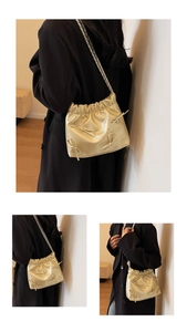 Detail of light gold pleated handbag with delicate metallic bows and chain strap