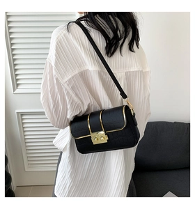 Detail of black crocodile texture bag with gold square buckle on white pleated top