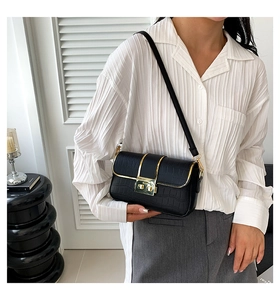 Detail of black crocodile texture shoulder bag with premium gold clasp and buckle