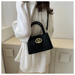 Detailed side view of black quilted PU leather handbag with gold heart-shaped logo lock