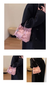 Detail of pink leather drawstring bucket bag featuring cute bow accents and silver chain