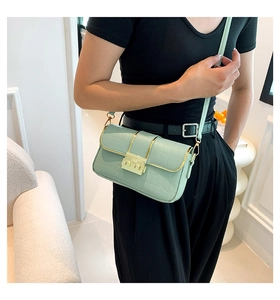 Detail of mint green crocodile pattern crossbody bag with golden clasp on model
