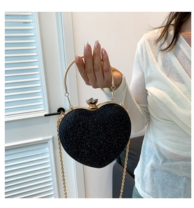 Detail of black heart shaped evening bag with sequins and golden metal chain handle