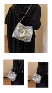Detail of silver pleated bucket bag featuring metallic bows and sleek chain strap