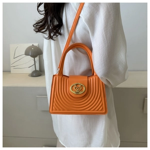 Detail of bright orange heart-shaped crossbody bag with gold hardware and creative stitching