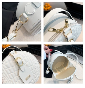 Close-up of golden hardware and crocodile-textured leather on white circular bag