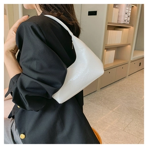 Dettaglio della trama a coccodrillo bianco su una borsa a spalla a forma di mezzaluna