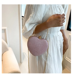 Close-up of pink heart-shaped evening bag with golden handle and glitter finish