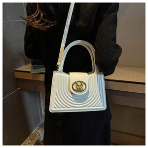 Detailed close-up of a white quilted shoulder bag with golden hardware and wavy stitching