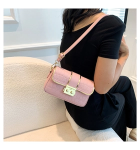 Close-up of pink croc-effect crossbody bag with elegant gold clasp on a model