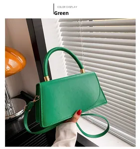 Dettaglio della borsa in pelle verde con hardware dorato e manico rotondo rinforzato