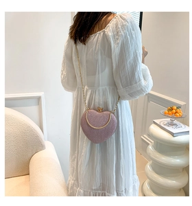 Détail d'un sac à main cœur à paillettes roses avec chaîne dorée porté par un mannequin
