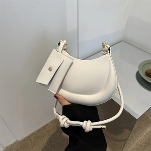 Minimalist white matte leather crescent shoulder bag with side pouch and knotted strap