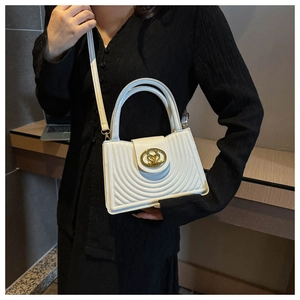Close-up of white crossbody bag featuring quilted patterns and golden metallic round buckle