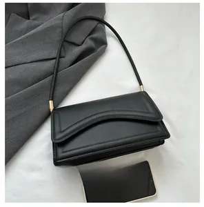 Detail view of black faux leather shoulder bag with gold hardware and phone size reference