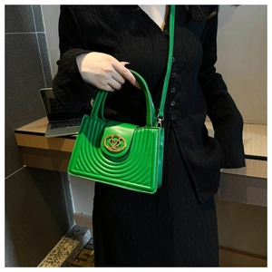 Groene geplooide crossbodytas met goudkleurig slot gedragen door model in zwart