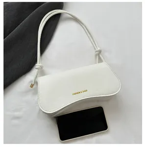 Détail du sac blanc à texture crocodile avec logo doré et bandoulière décorative nouée