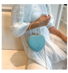 Detail of glittery heart-shaped handbag with golden ring handle and metal chain strap