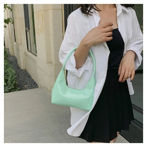 Primo piano della borsa verde menta con motivo a coccodrillo portata da una modella