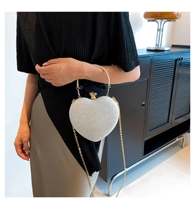 Detail of silver glitter heart bag with gold ring handle and metal chain strap