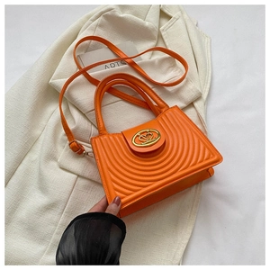 Detail of orange textured PU leather bag featuring gold V-heart metal lock and top handle