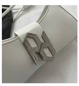 Detail of silver geometric RD metal clasp on white leather crossbody handbag